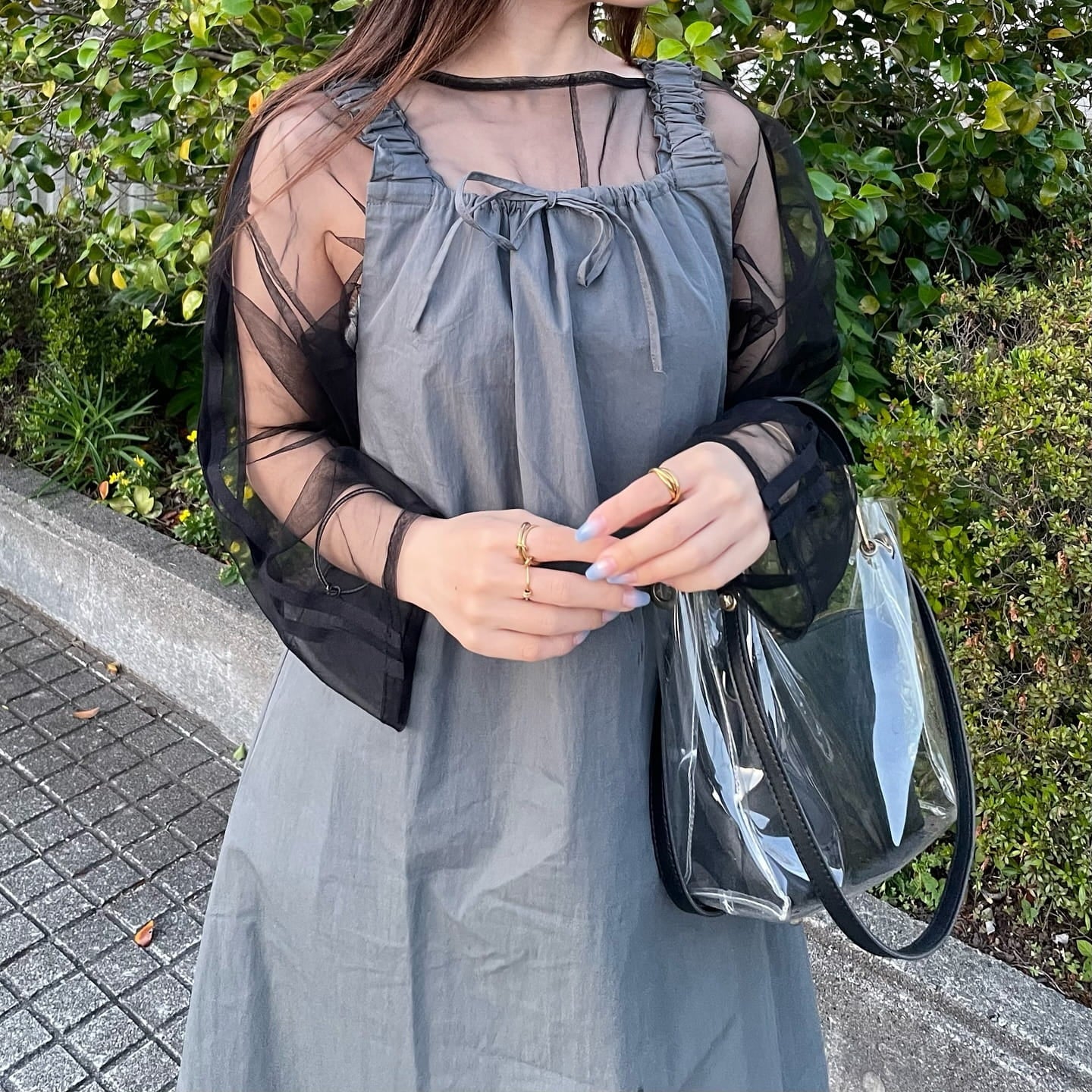 ブラックサンダルとクリアバッグを合わせたグレーワンピースの夏コーデとゴールドリング