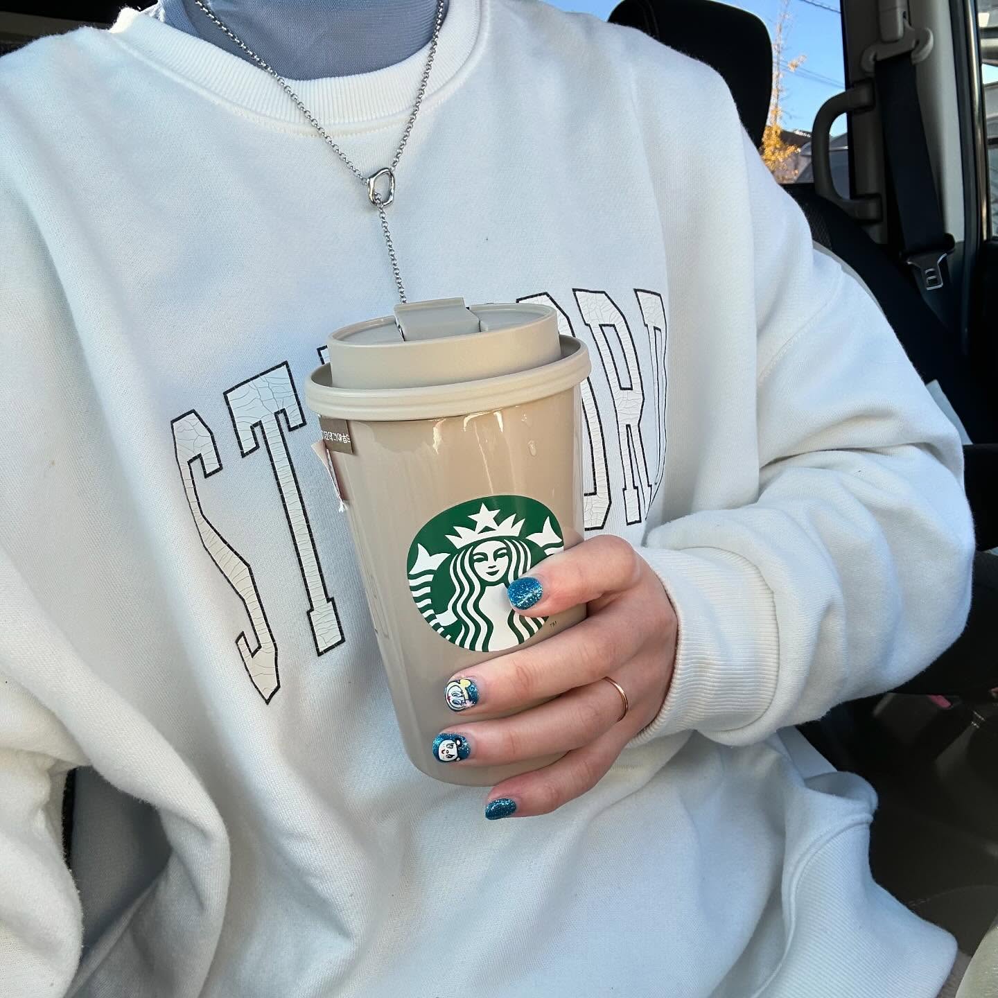 白スウェットにY字シルバーネックレスを合わせ、タンブラーを持つカジュアルコーデの胸元アップ