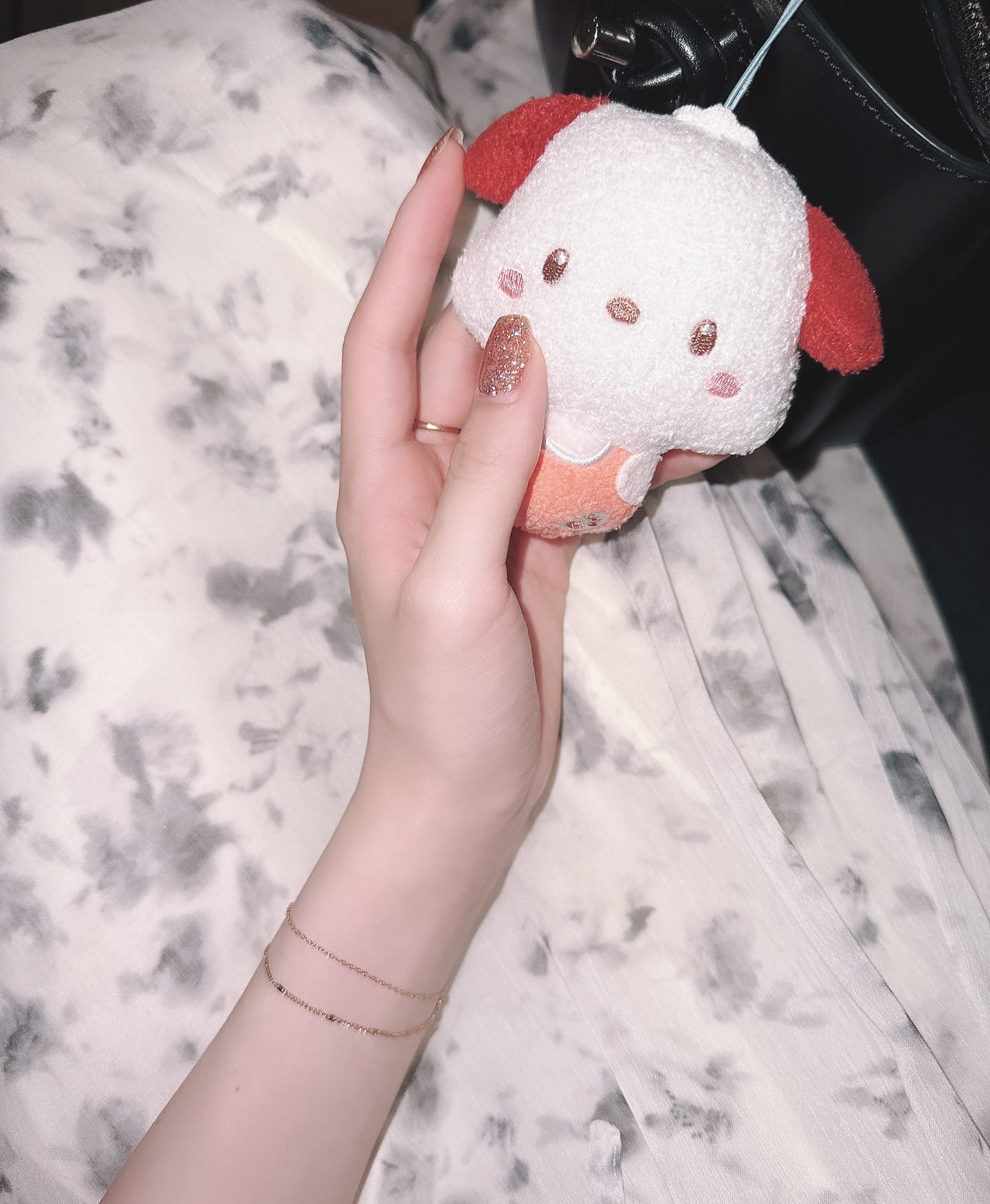 ブレスレットを着けた手元で小さなぬいぐるみを持つ、やわらかな雰囲気の手元アップ