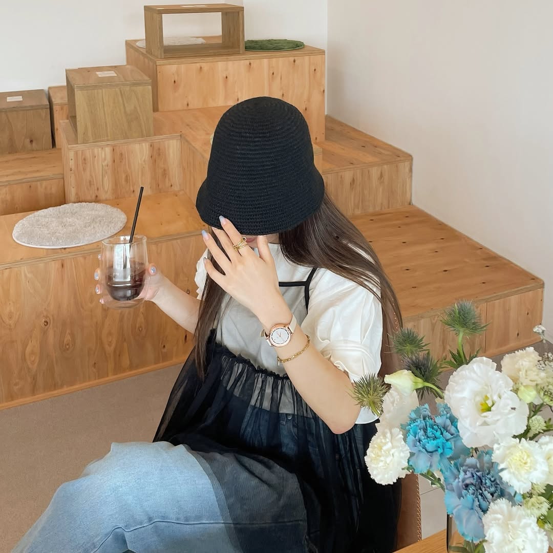 店内カフェでドリンクを持ち、ブレスレットと腕時計を重ねた手元コーディネート